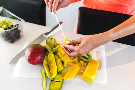 A woman putting the sliced juicy mangos on the wooden stickの写真素材