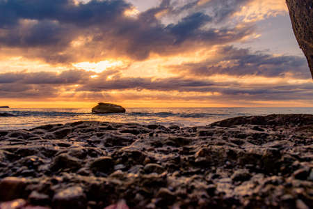A breathtaking scenery of a rocky beach on a beautiful sunset backgroundの写真素材