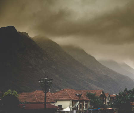 Old houses in Armenian village with dark grey skies in backgroundの写真素材