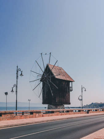 A vertical shot of a small wooden windmill on the side of the road in the countrysideの写真素材