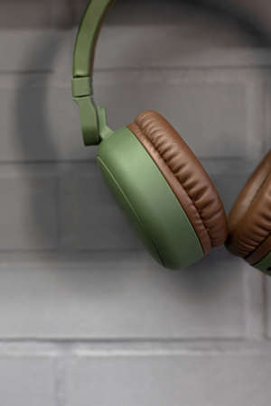 A vertical shot of green headphones hanging on a brick wallの写真素材
