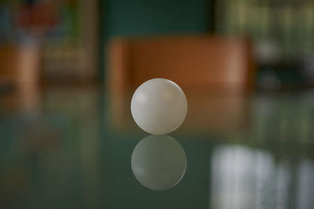 A shallow focus closeup shot of a white table tennis ball on a glass tableの写真素材