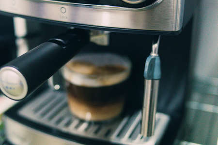 A closeup shot of espresso being poured in a glass with a coffee making machineの写真素材