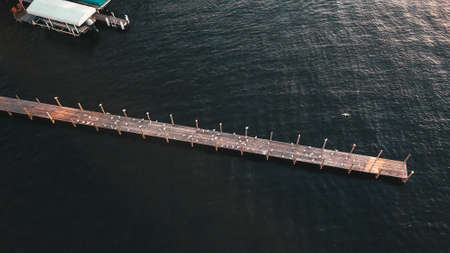 An aerial shot of a long wooden pier and amazing texture of the waterの写真素材