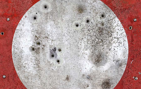 A closeup shot of bullet holes on an old rusted street signの写真素材