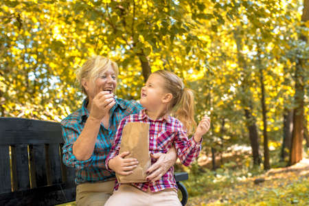 A smiling grandmother hugging her female grandchild in the park