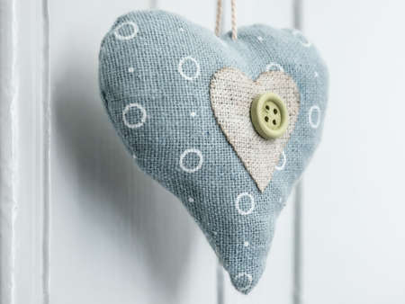 A closeup shot of a heart-shaped object made of a button and circle-patterned fabricの写真素材
