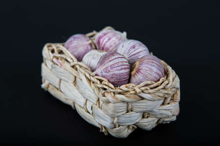 A closeup shot of peeled onions in a woven basket with a black backgroundの写真素材