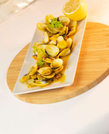 A close up shot of delicious looking clam with a side of lemon and cilantro on top