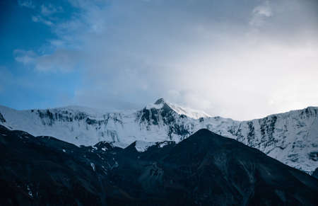The breathtaking view of the snow-covered mountain peak captured under the clouds in the skyの写真素材