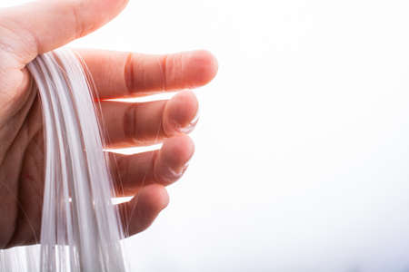 A closeup shot of a human hand holding white threads isolated on the white backgroundの写真素材