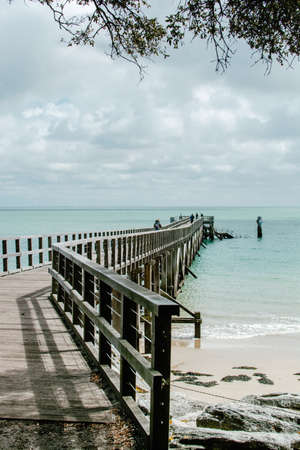 A vertical shot of the beautiful view of the ocean with a wooden pier on the coastの写真素材