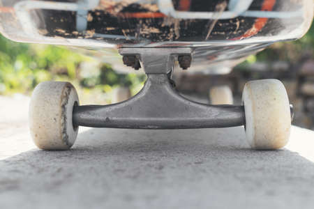 A closeup of a skateboard on the ground under the sunlight with a blurry background