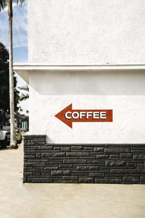 A red arrow sign on a white building with a writing COFFEE on it