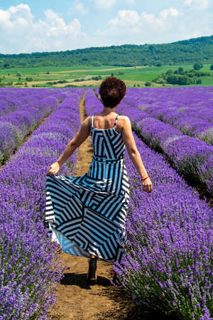 A vertical shot of a female in a sundress in a lavender field under the blue skyの写真素材