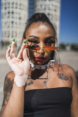 A shallow focus of a young African female with flame glasses and tattoos in Spain