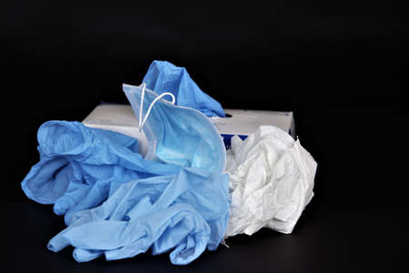 A closeup shot of a bottle of hand sanitizer and latex gloves isolated on a black background -...