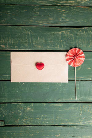 Small heart on a letter with decorative umbrella and green wooden backgroundの写真素材