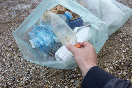 A person picking up the garbage on the seacoast - environmental pollution concept
