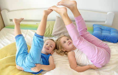 A female child and a male child playing and having fun on a bedの写真素材