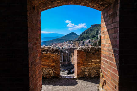 A brick made doorway with a view of the  city near hills in the distance at daytime