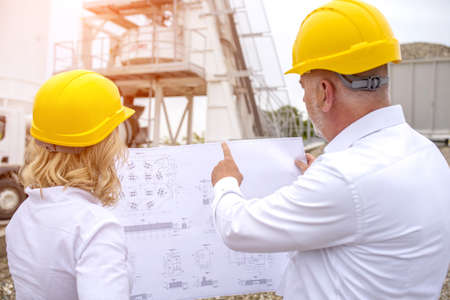 Two engineers on site wearing safety helmets and discussing the project details