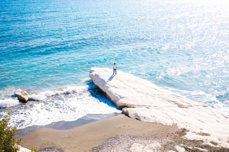 A male standing on the coast of a sea during a sunny dayの写真素材