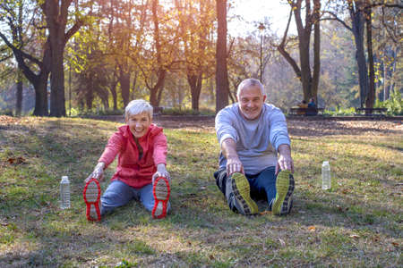 Active senior male and female exercising in the park in autumnの写真素材
