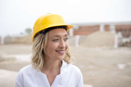 A shallow focus of a young female construction worker with a yellow helmet at daytimeの写真素材