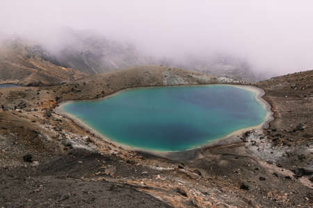 A beautiful aerial shot of a small lake in the middle of the desert near a mountain on a foggy dayの写真素材