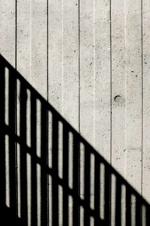 Concrete wall with vertical lines and a staircase shadow