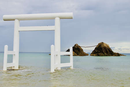 A selective shot of a Japanese white gate in Itoshima beach with cliffs visible in the backgroundの写真素材