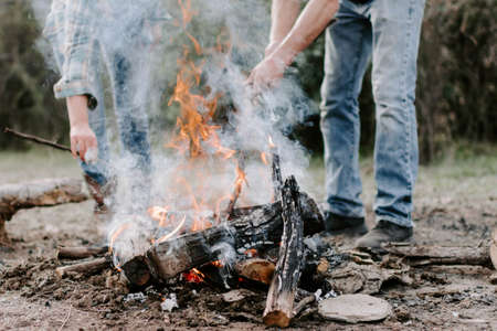 A closeup of people making a bonfire in the forest