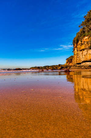 A sunny scenery of a beautiful sandy beach on a blue seascape backgroundの写真素材