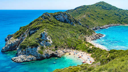 A bird-eye shot of an island and Porto Timoni beach surrounded by beautiful blue water during...
