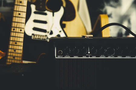 A selective shot of a black amplifier near a black electric guitar