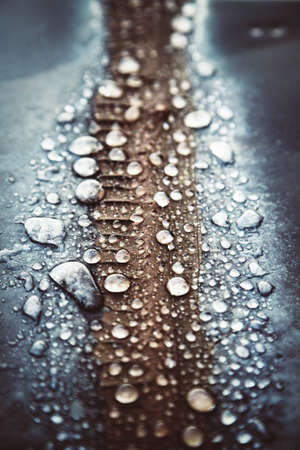 A vertical selective shot of raindrops on a brown and blue surface
