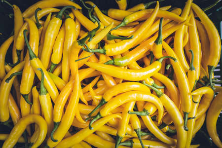 A high angle shot of a pile of yellow peppers in a market