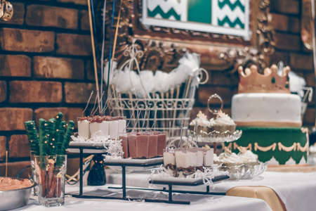 A selective focus shot of green sticks, souffles, cupcakes and a decorated cake on white table