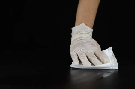 A person with gloves wiping the floor with tissue isolated on a black backgroundの写真素材