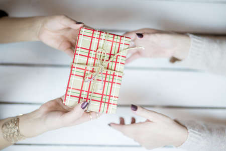 An overhead selective closeup shot of a person giving a wrapped gift box to another personの写真素材