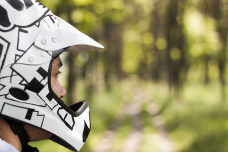 A shallow focus shot of a caucasian male wearing a cool patterned motorcycle helmet outdoors
