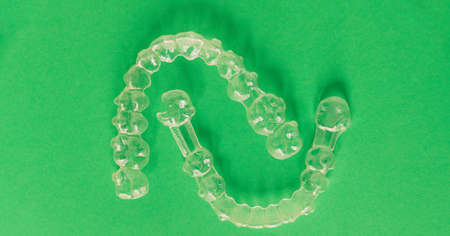 A top view of transparent aligners isolated on a green background