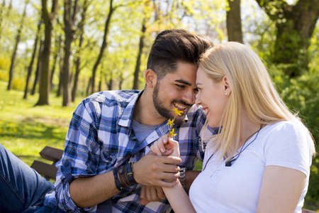 An attractive young couple flirting and having fun on a park benchの写真素材