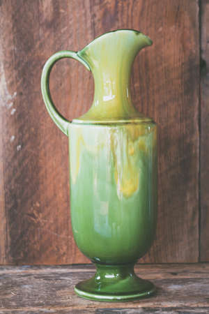 A closeup shot of a green ceramic vintage vase on a wooden background