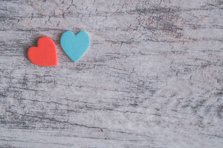 An overhead shot of a blue and a red heart on a wooden surface with space for text