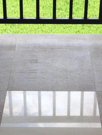 A vertical shot of ceramic floor reflecting the metal fence
