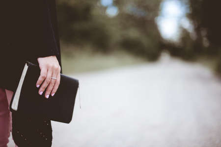 A selective closeup shot of a person holding a black thick notebookの写真素材