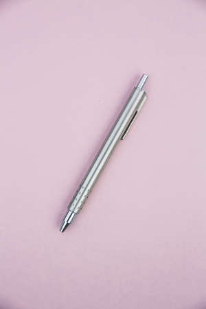 A high angle shot of a silver click pen on a pink surfaceの写真素材