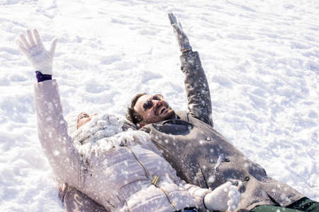 A young attractive laying down and playing with snow in a winter wonderland parkの写真素材